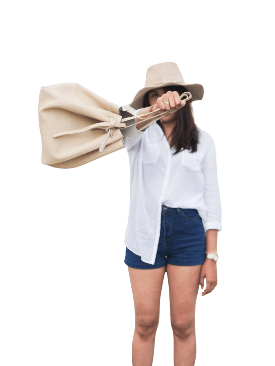 Being a trend, the Alice tote bag is a favorite because of its stylistic appearance and it can fit a lot of things. A woman in a hat wearing a white shirt and blue jeans showing off an alice tote that seems to match her outfit. The drawstring ribbon as the main cover of the bag keeps the bag secure, even when it is pushed forward as shown in the picture. So don't be afraid that the goods will be scattered