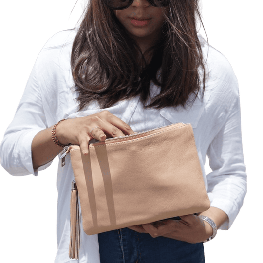 A model shows a 2in1 leather Clutch. It has a zip as a main compartment, and a detachable tassel to make it more stylist. It is Cloe 2in1 Leather Clutch from Seminyak Leather Bali in Nude Pink color.