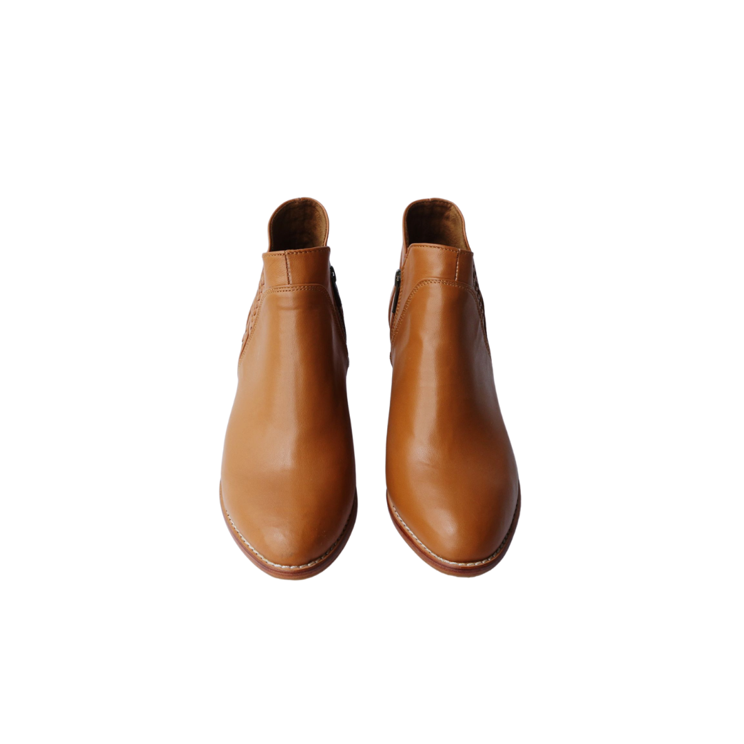 Ankle boots with elastic and zipper closure, featuring handwoven V-shaped detailing around the ankle. 5 cm block heels. Made from sheep leather, available in black and tan colors. A blend of style and comfort for a modern and versatile look.