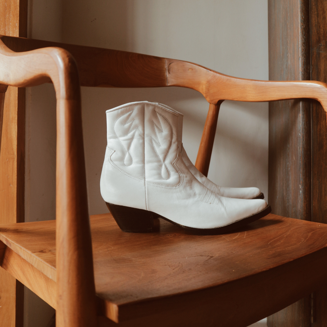 Ankle boots with handstitched detailing, featuring zipper closure and carved metal accents on the toe cap and heel. 5 cm wooden heel in a classic black finish. Stylish footwear inspired by cowboy/ western ankle boots for a touch of rustic charm and modern allure.