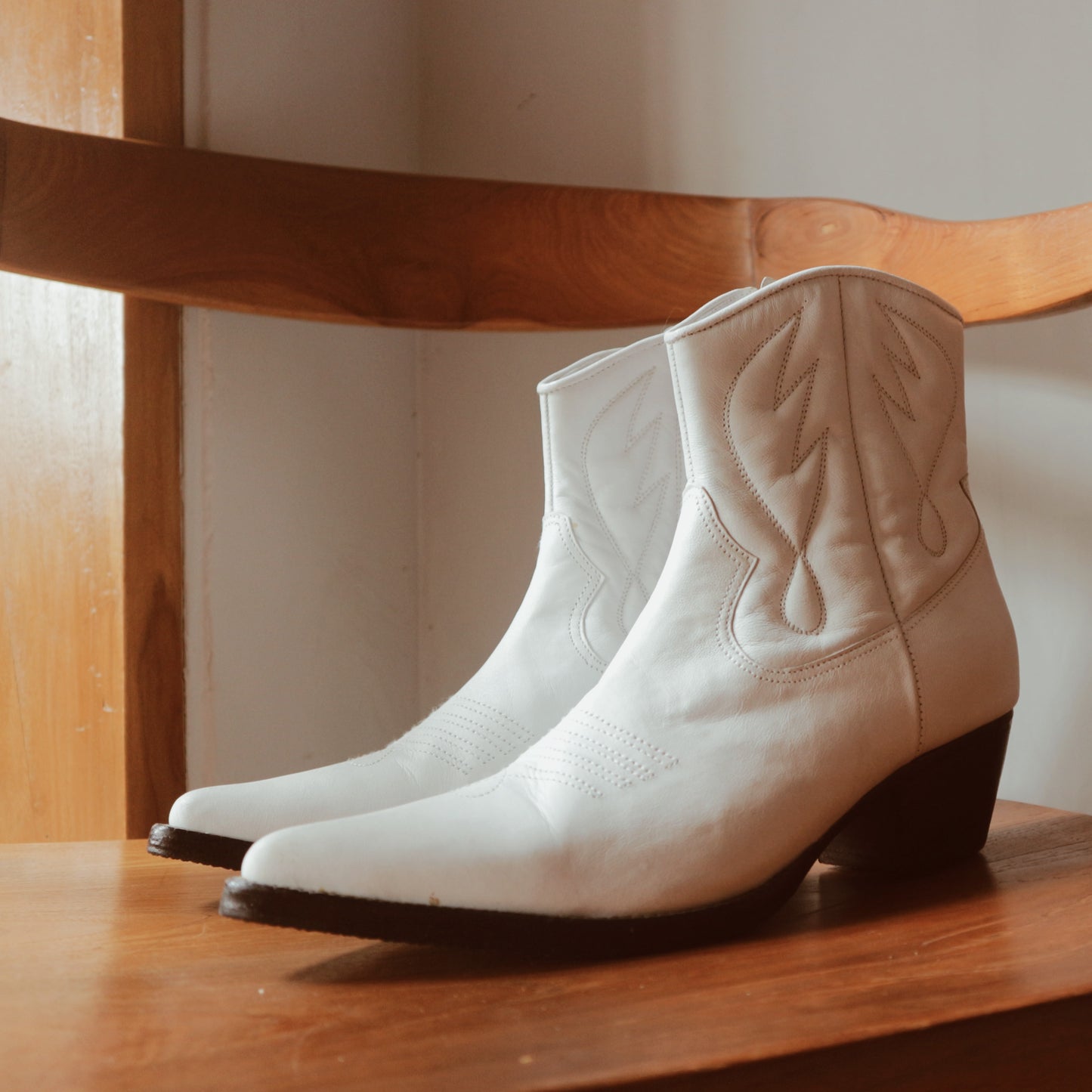Ankle boots with handstitched detailing, featuring zipper closure and carved metal accents on the toe cap and heel. 5 cm wooden heel in a classic black finish. Stylish footwear inspired by cowboy/ western ankle boots for a touch of rustic charm and modern allure.