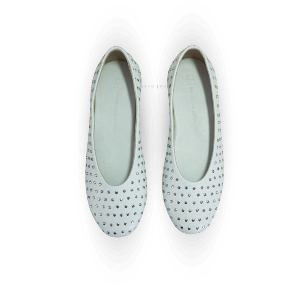 A pair of white ballet shoes with silver accessories displayed against a white background designs by Seminyak Leather Bali
