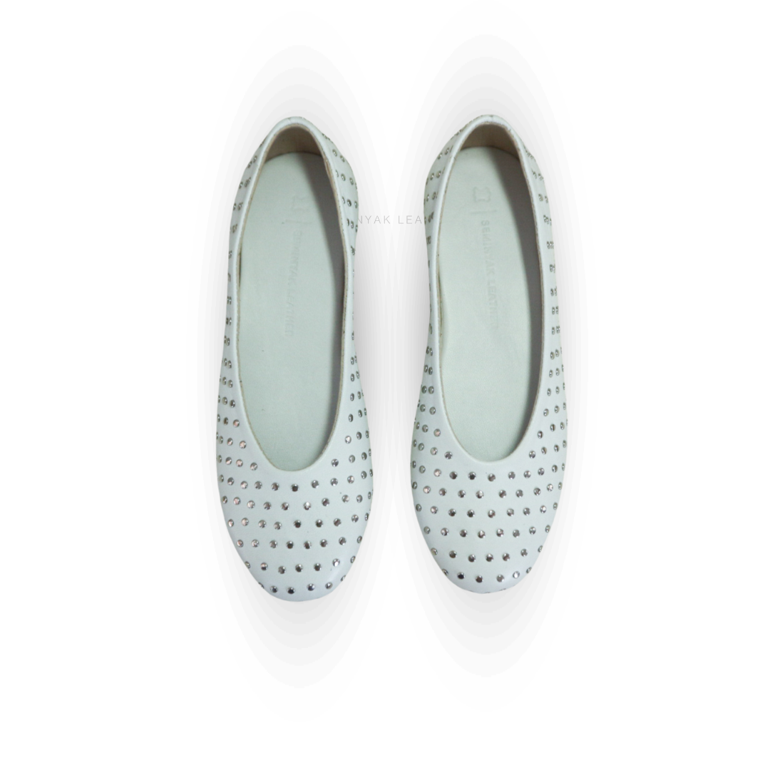 A pair of white ballet shoes with silver accessories displayed against a white background designs by Seminyak Leather Bali