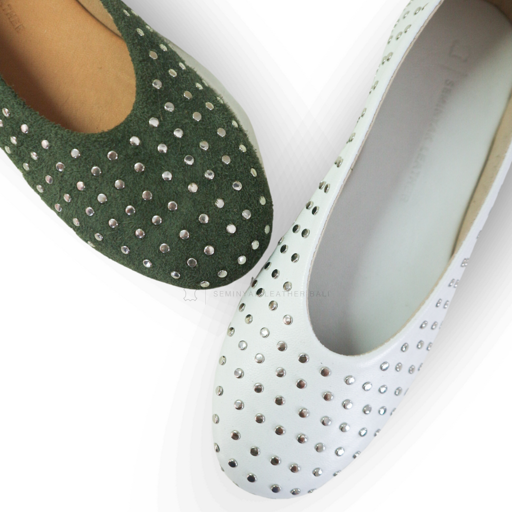 A pair of olive white ballet shoes with silver accessories displayed against a white background designs by Seminyak Leather Bali