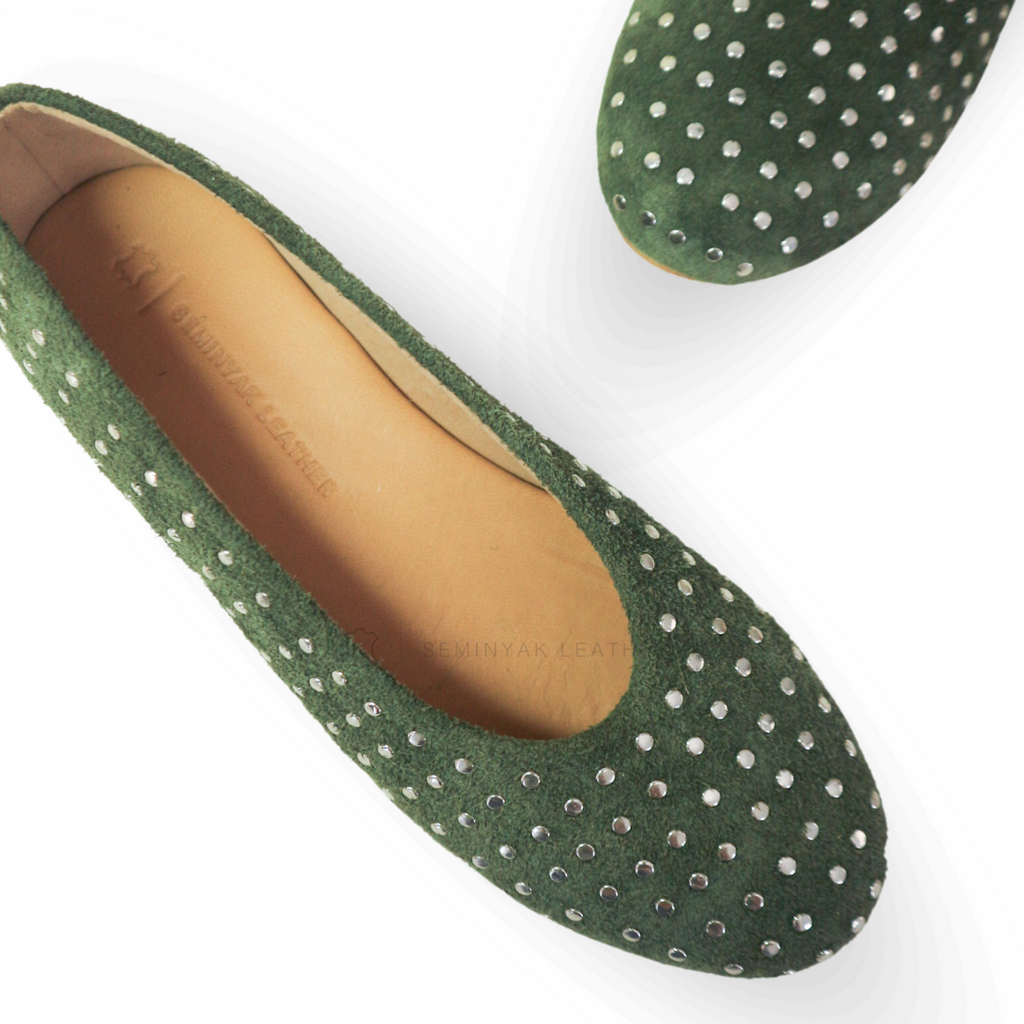 A pair of olive ballet shoes with silver accessories displayed against a white background designs by Seminyak Leather Bali