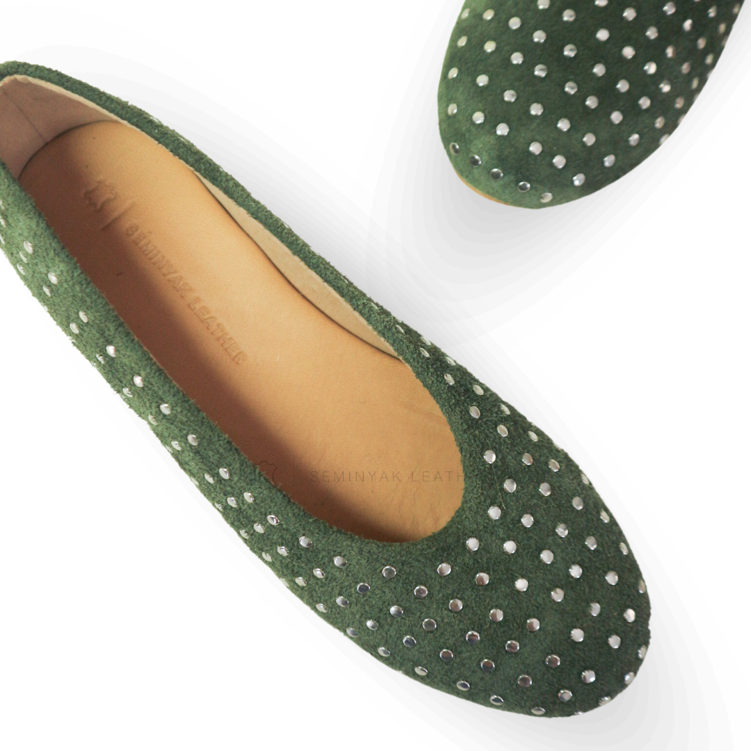 A pair of olive ballet shoes with silver accessories displayed against a white background designs by Seminyak Leather Bali