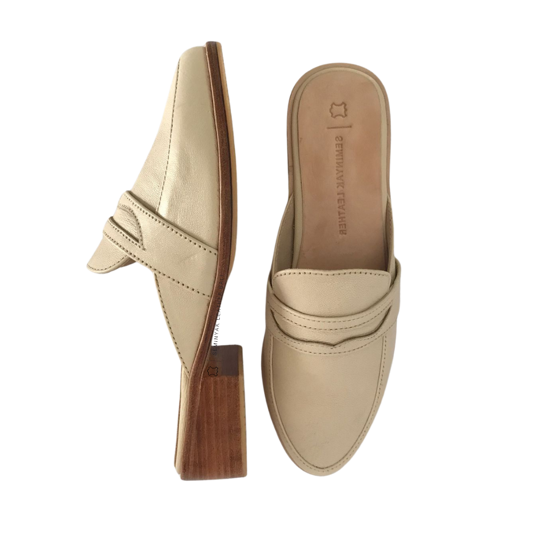 A pair of ivory loafer mules with wooden heels, displayed against a white background designs by Seminyak Leather Bali