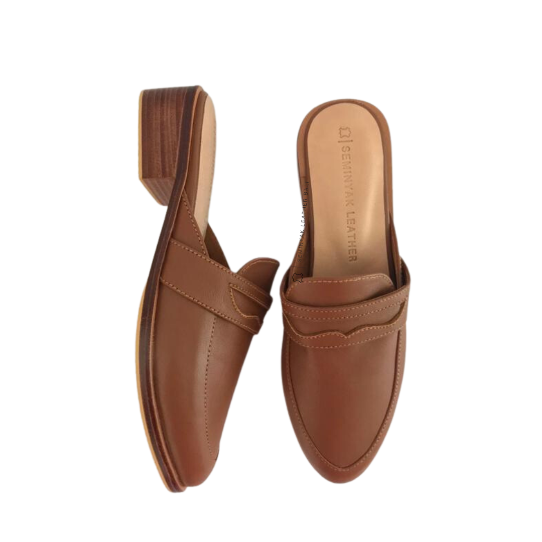 A pair of brown loafer mules with wooden heels, displayed against a white background designs by Seminyak Leather Bali