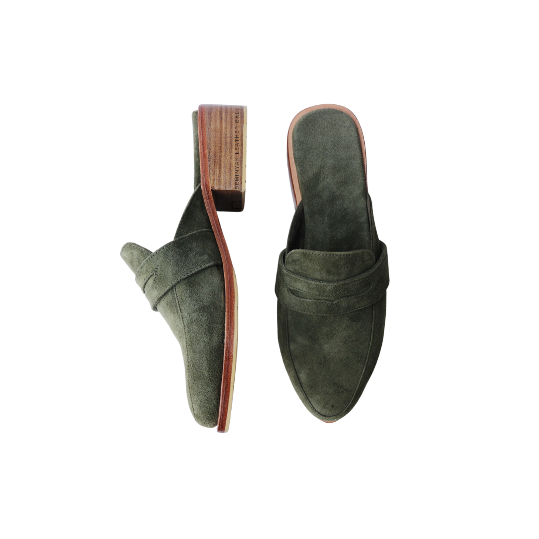 A pair of olive suede loafer mules with wooden heels, displayed against a white background designs by Seminyak Leather Bali