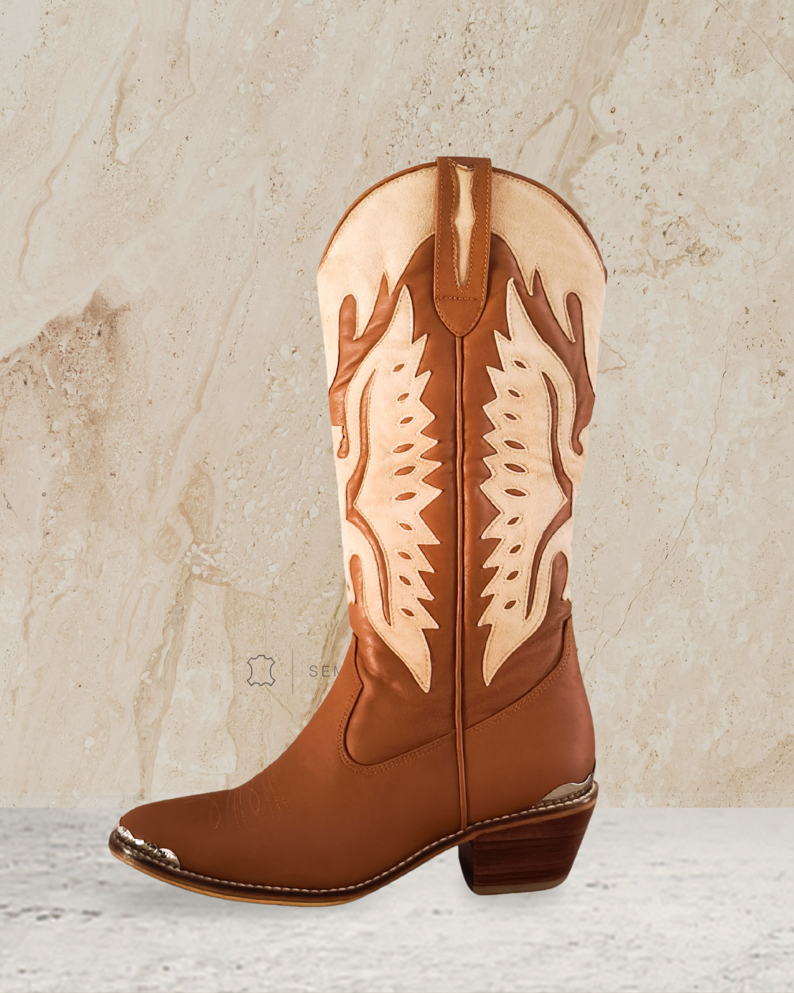knee high cowboy boot with decorative patterns designs by Seminyak Leather Bali on a textured beige background