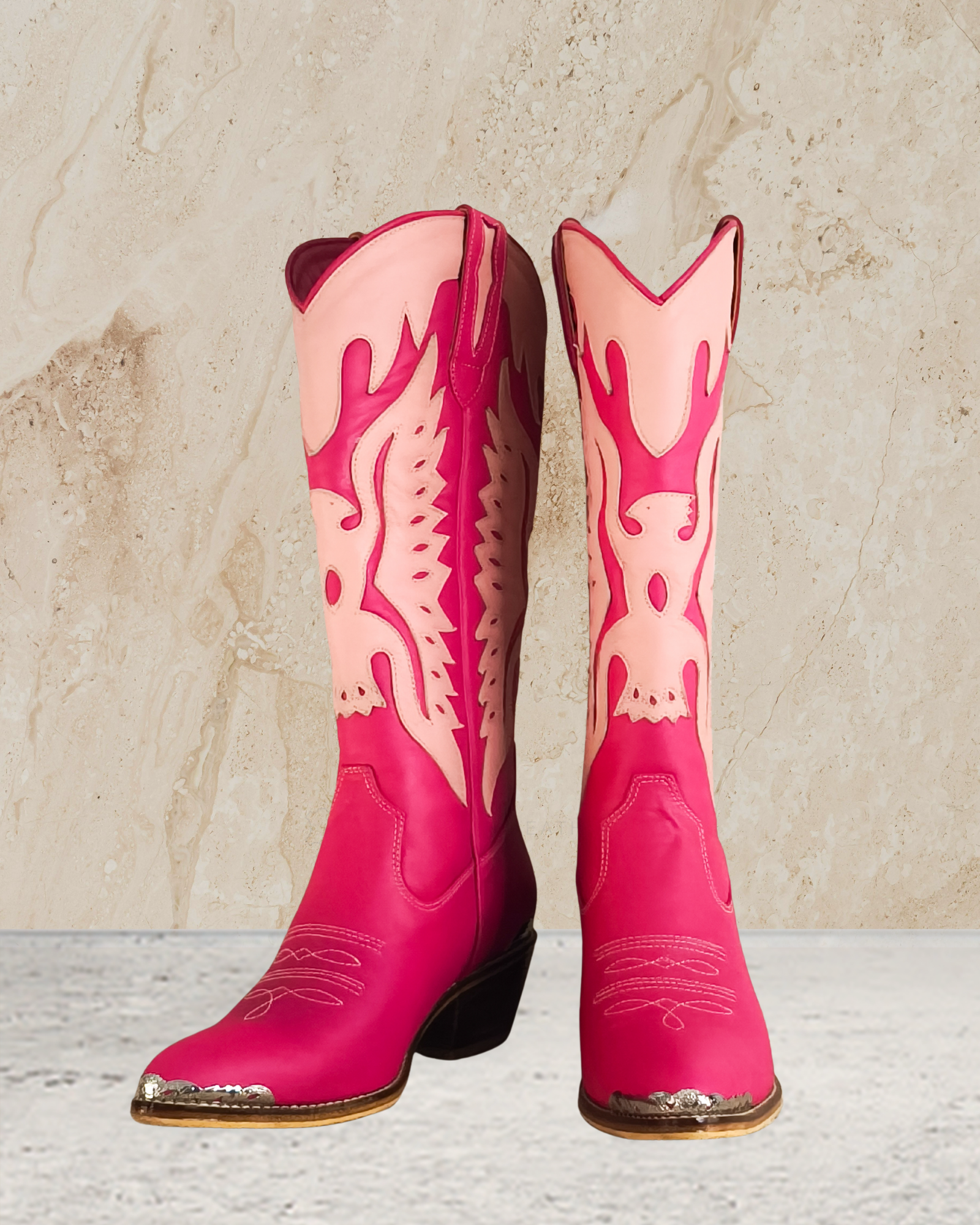 Pink knee high cowboy boot with decorative patterns designs by Seminyak Leather Bali on a textured beige background