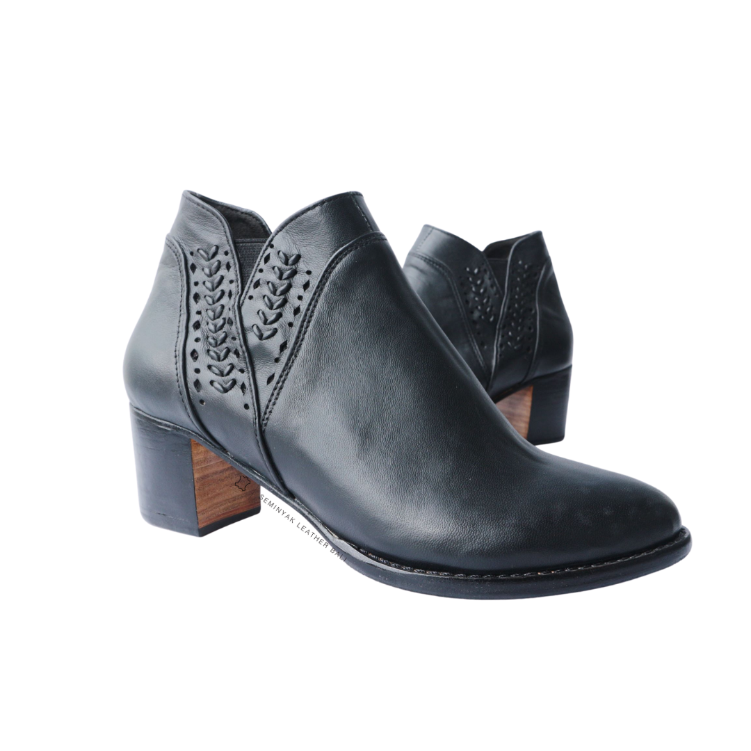A pair of black ankle boots with handwoven detailing around the ankle and a block heel designs by Seminyak Leather Bali.