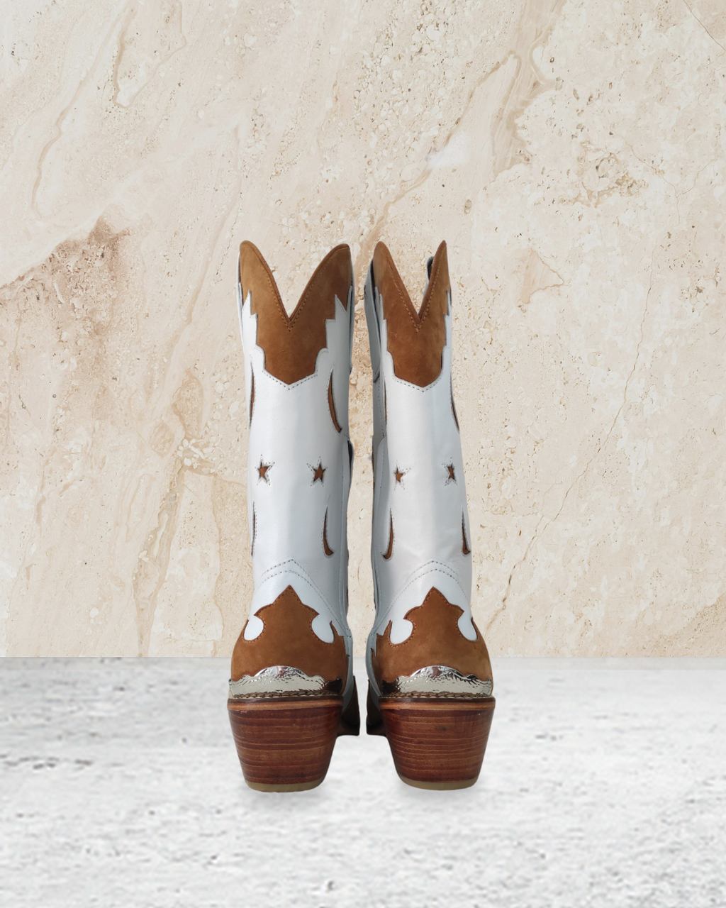 White cowboy boot with brown accents designs by Seminyak Leather Bali on a textured beige background