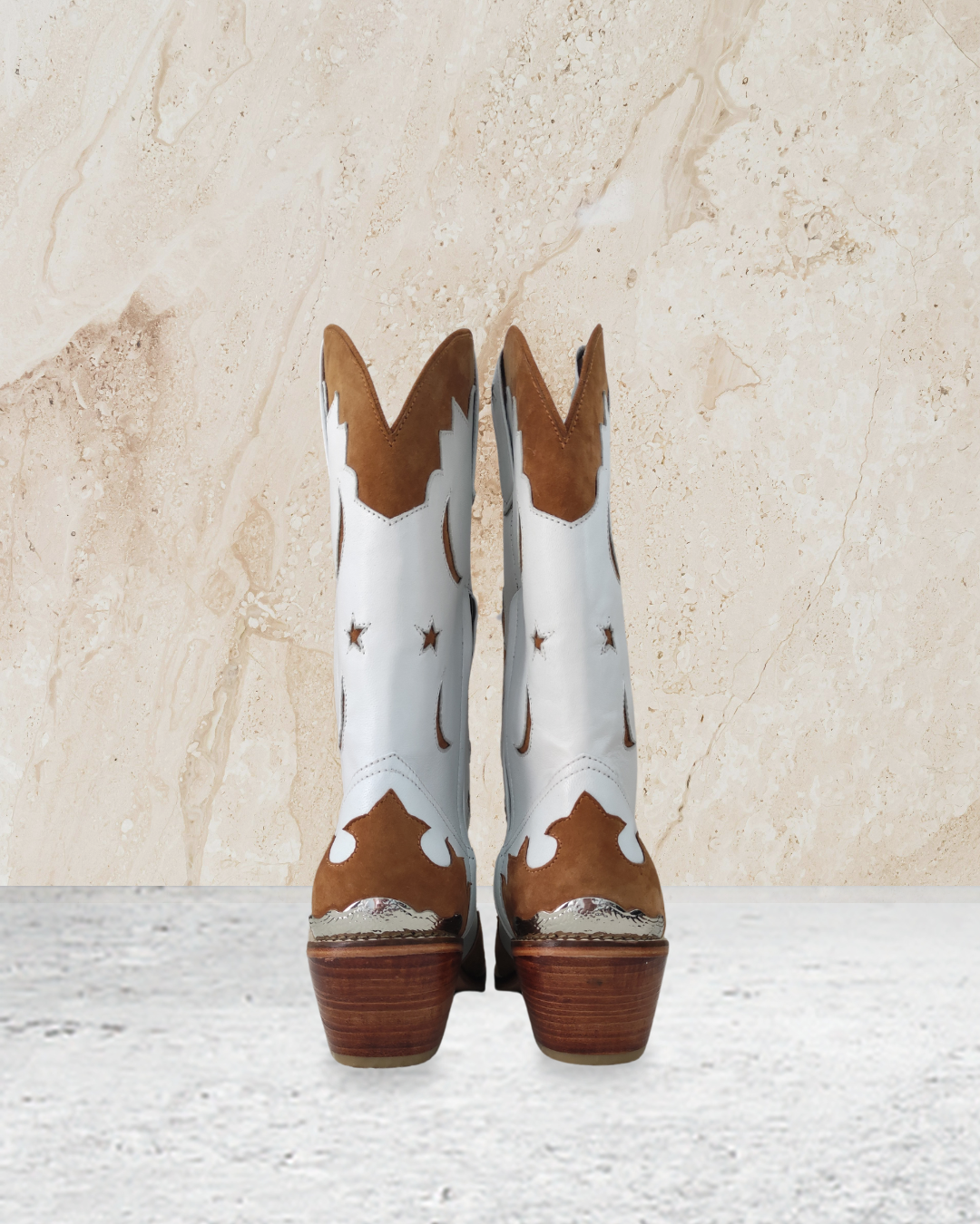White cowboy boot with brown accents designs by Seminyak Leather Bali on a textured beige background