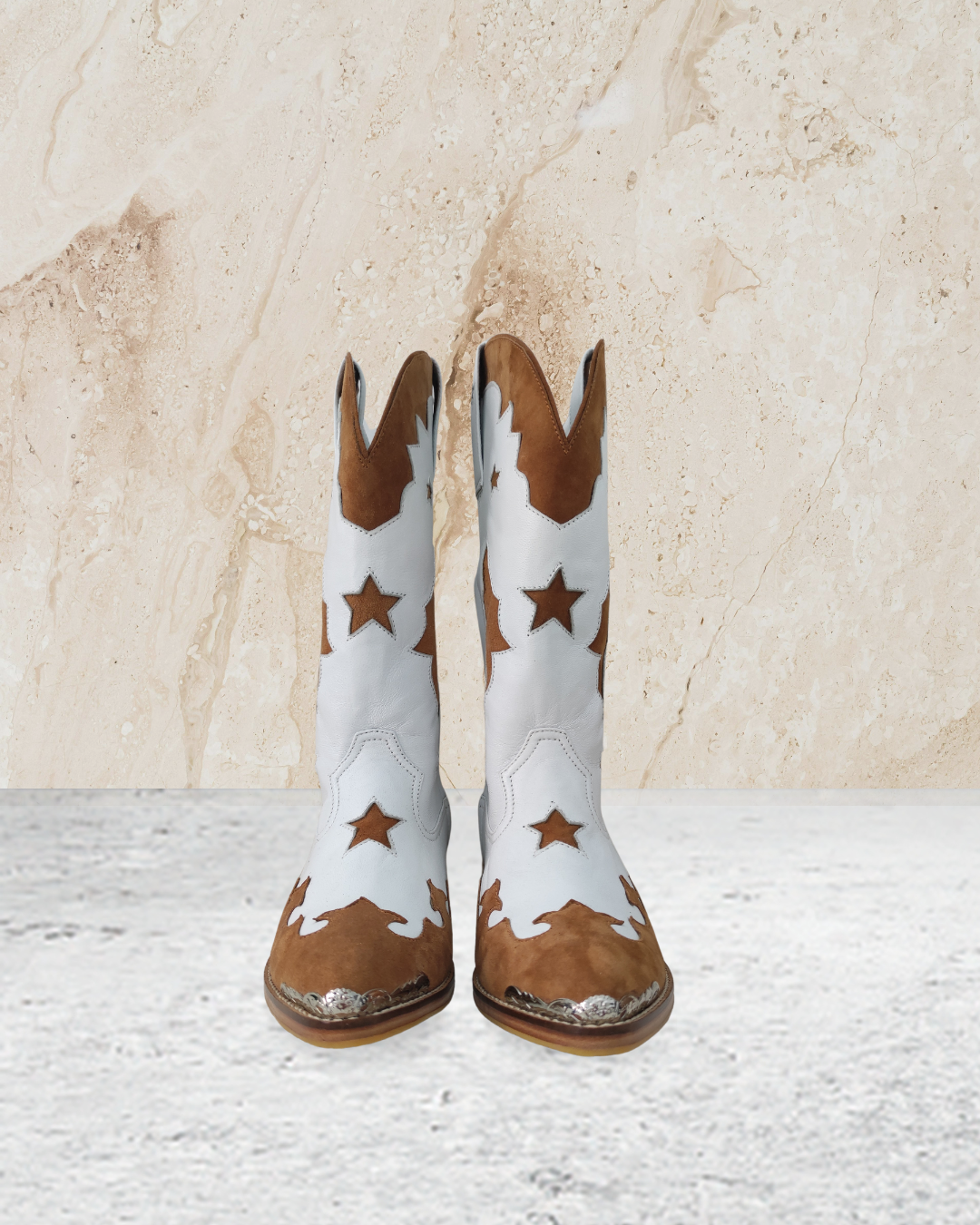 White cowboy boot with brown accents designs by Seminyak Leather Bali on a textured beige background