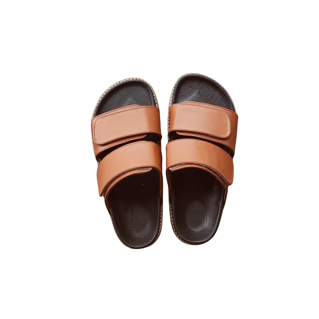 A pair of tan sandal with double strap velcrow, displayed against a white background designs by Seminyak Leather Bali