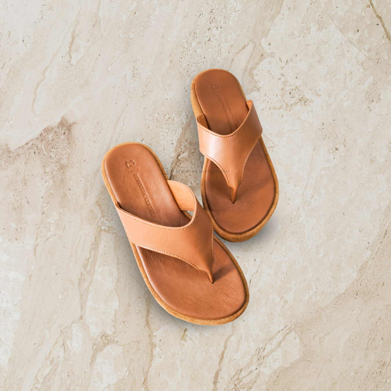 A pair of honey tan sandals with a platform sole designs by Seminyak Leather Bali
