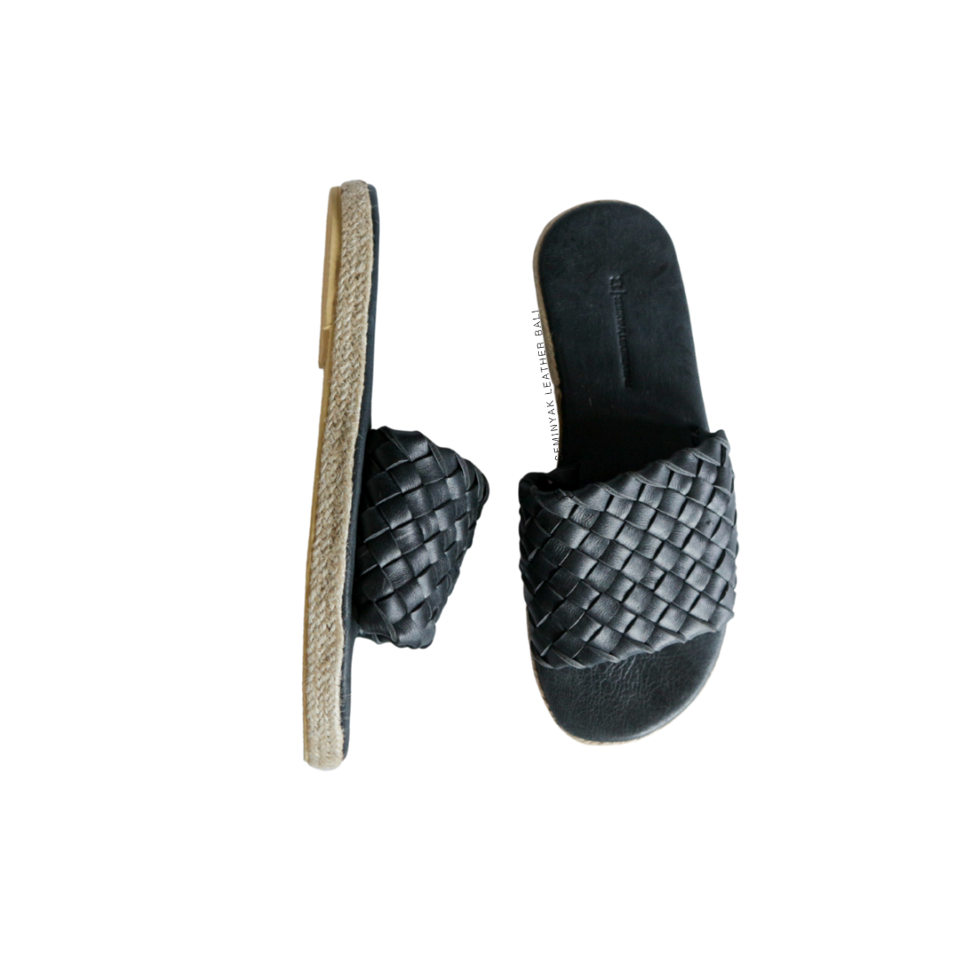 A pair of black wide woven strap sandals with a cushioned sole displayed against a white background designs by Seminyak Leather Bali