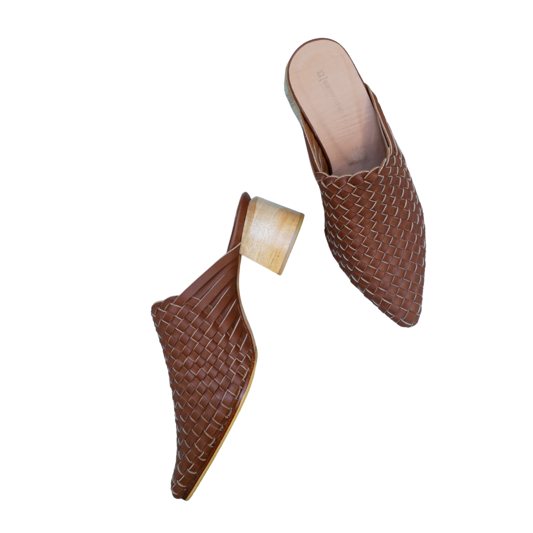 Pair of summer tan woven mule heels designs by Seminyak Leather Bali on a beige marble surface