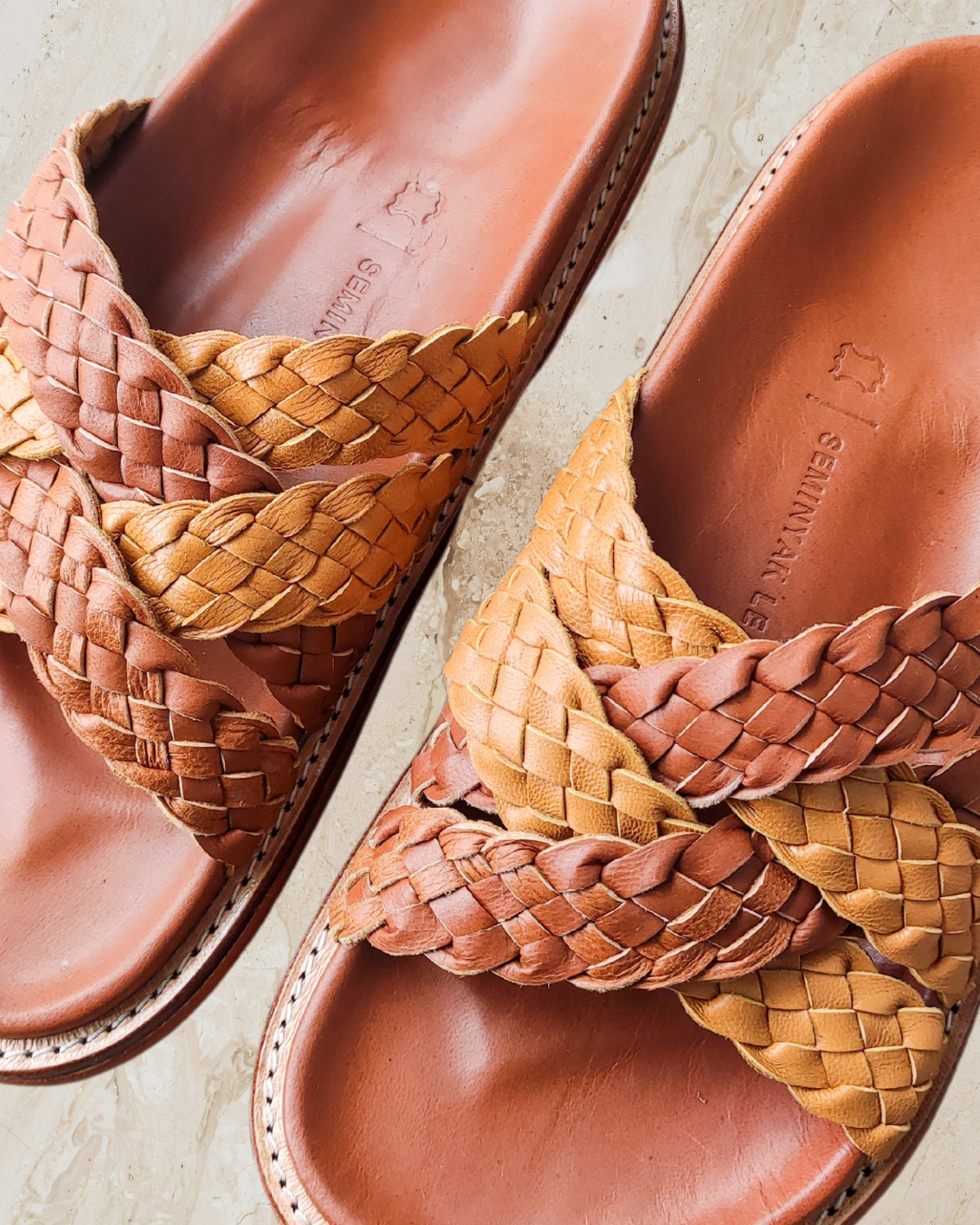 Pair of brown leather sandals with braided straps on a light background