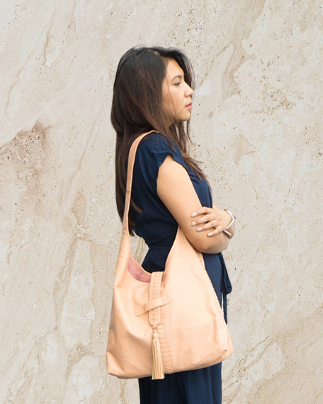 Person holding a blush shoulder bag against a neutral background designs by Seminyak Leather Bali