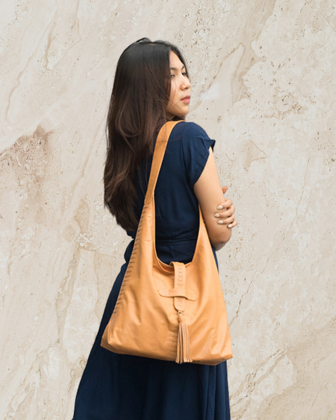 Woman carrying a tan leather bag against a neutral background designs by Seminyak Leather Bali