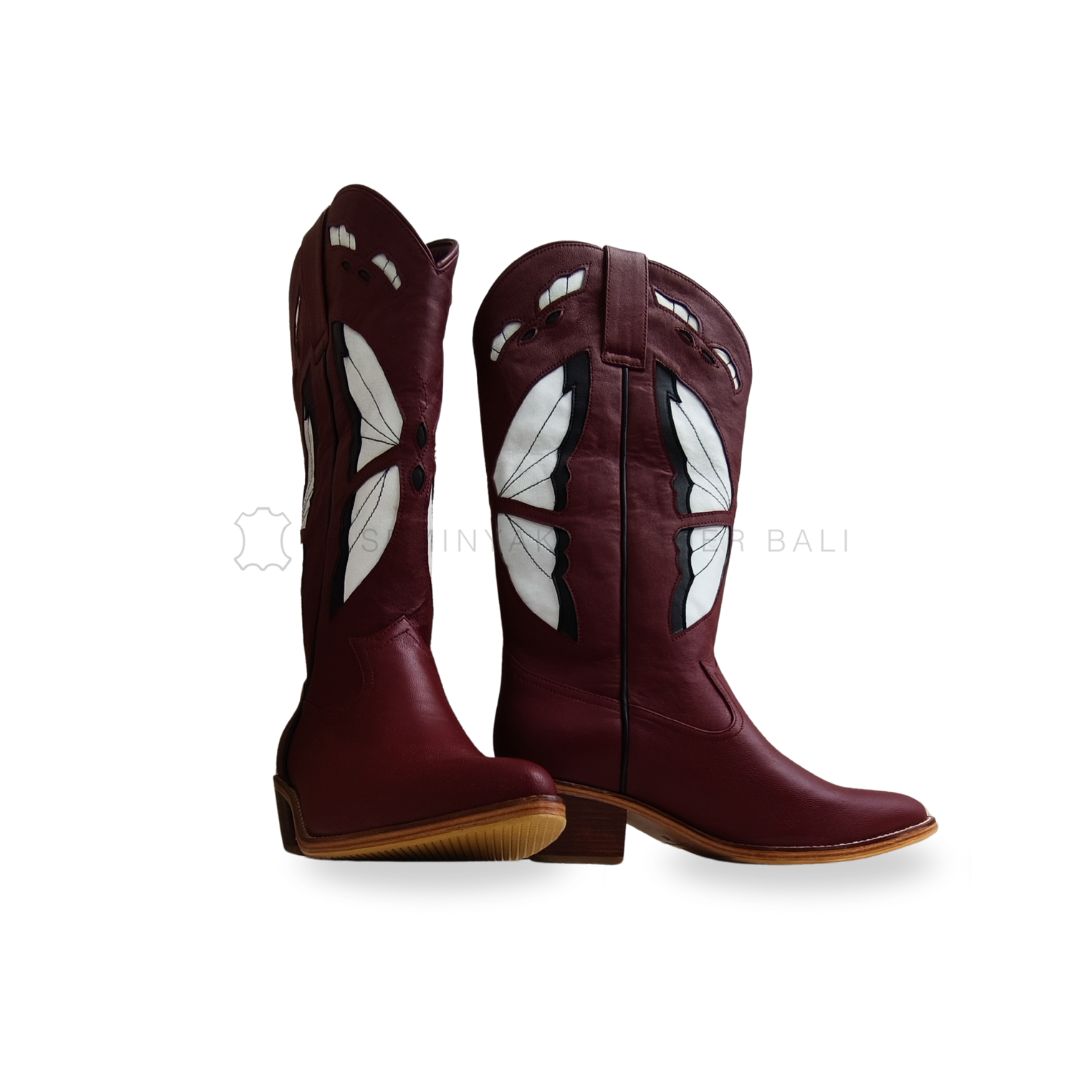 Pair of maroon cowboy boots with white wing designs on a white background