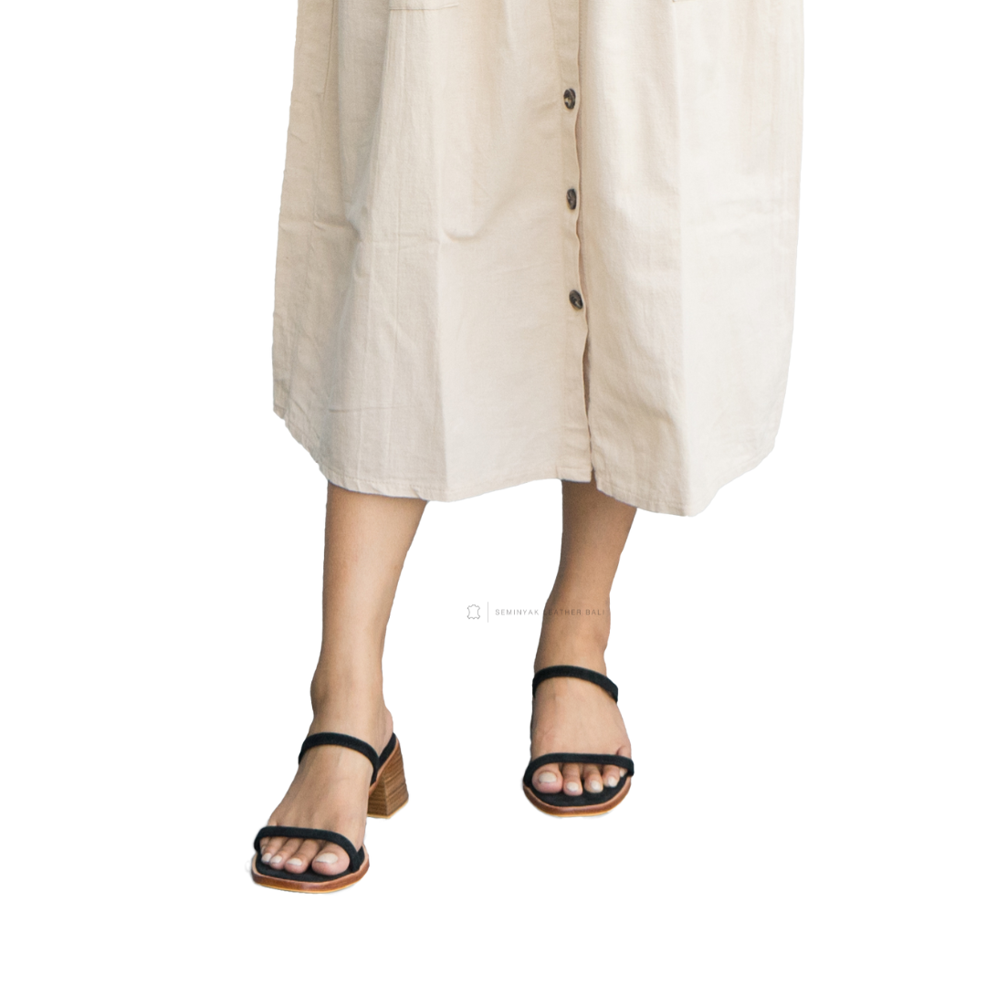Person wearing a beige button-up dress with sandals on a white background designs by Seminyak Leather Bali
