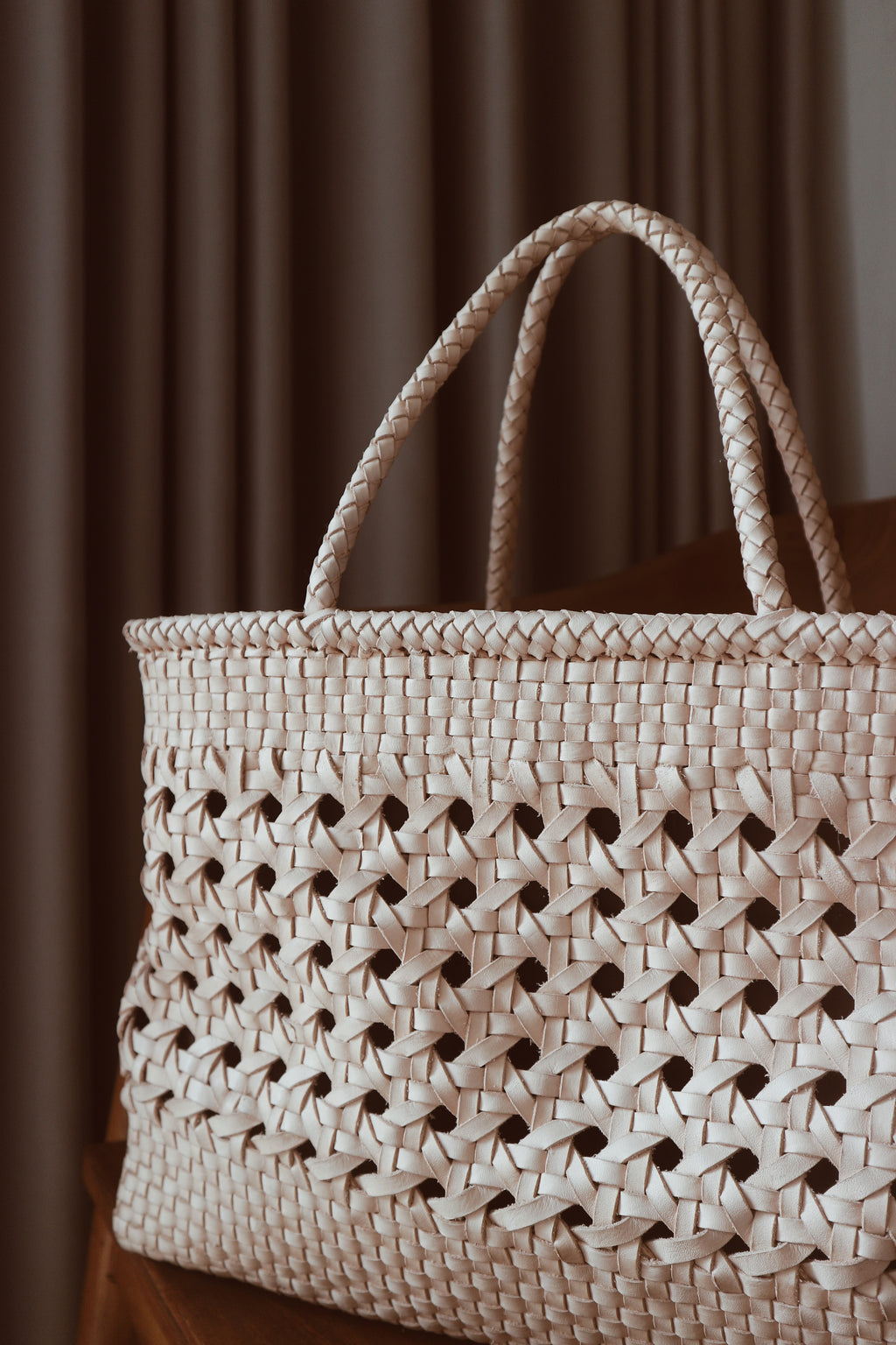 A blush medium-sized rectangle handbag made of hand-weaved leather with braided handle and chick-eye weave on the body by Seminyak Leather Bali. A blend of modern elegance and artisanal charm, crafted with meticulous attention to detail.