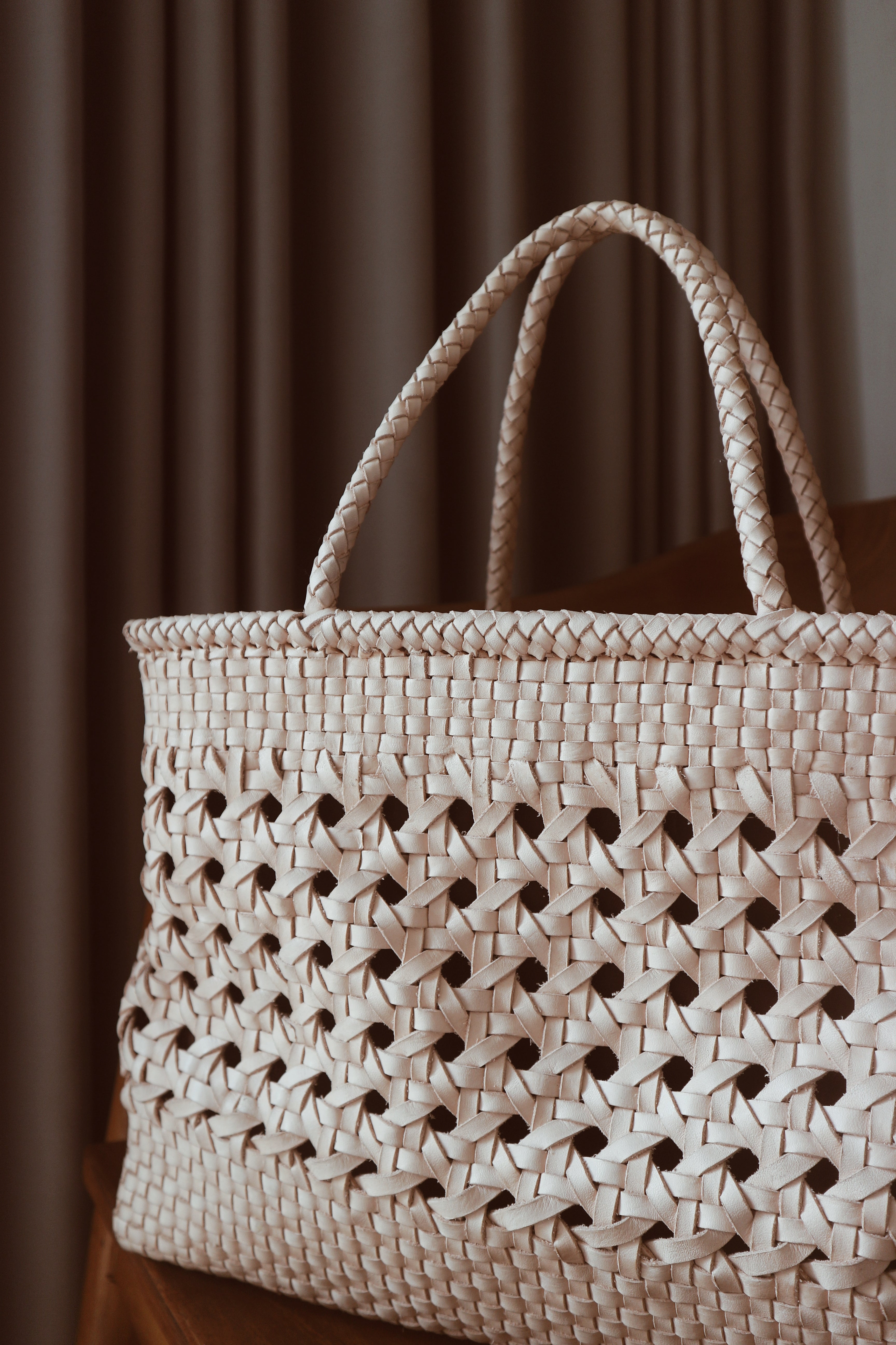 A blush medium-sized rectangle handbag made of hand-weaved leather with braided handle and chick-eye weave on the body by Seminyak Leather Bali. A blend of modern elegance and artisanal charm, crafted with meticulous attention to detail.