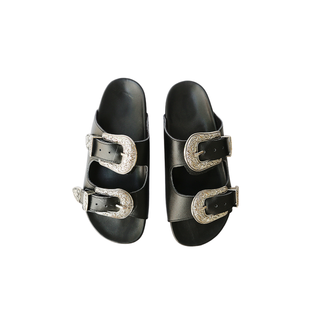 The image of a black sandal made of cowhide, designed with two straps and a carved buckle decoration is the Becky Slides Sandal from Seminyak Leather Bali