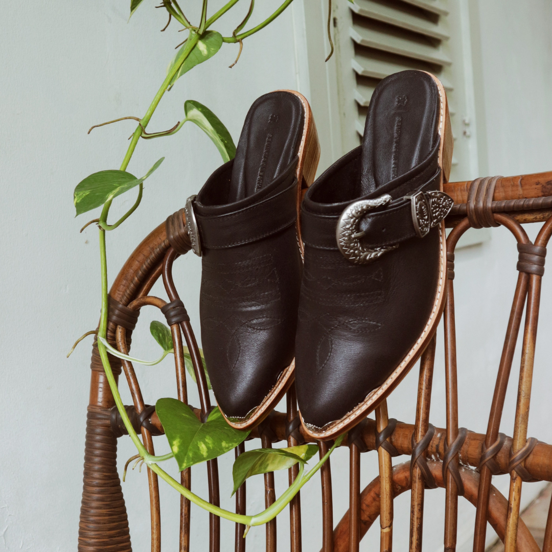 Black pointy toe mules by Seminyak Leather Bali with western-style stitching on vamp and carved metal toe cap. 5 cm wooden Cuban heel in a natural finish. A blend of Western charm and contemporary elegance, all made of leather.