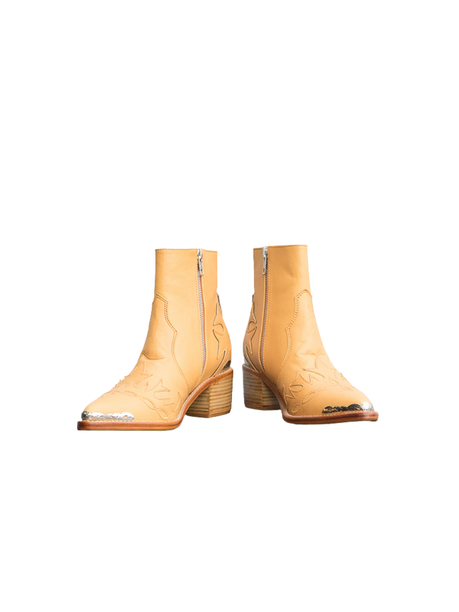 A picture of a Tan Boot, the boots are made of tan sheepskin with threaded carvings and additional metal carvings on the front and back as well as a ziper for ease of use and 5 cm high heels. These boots are Canggu Boots Carving from Seminyak Leather Bali