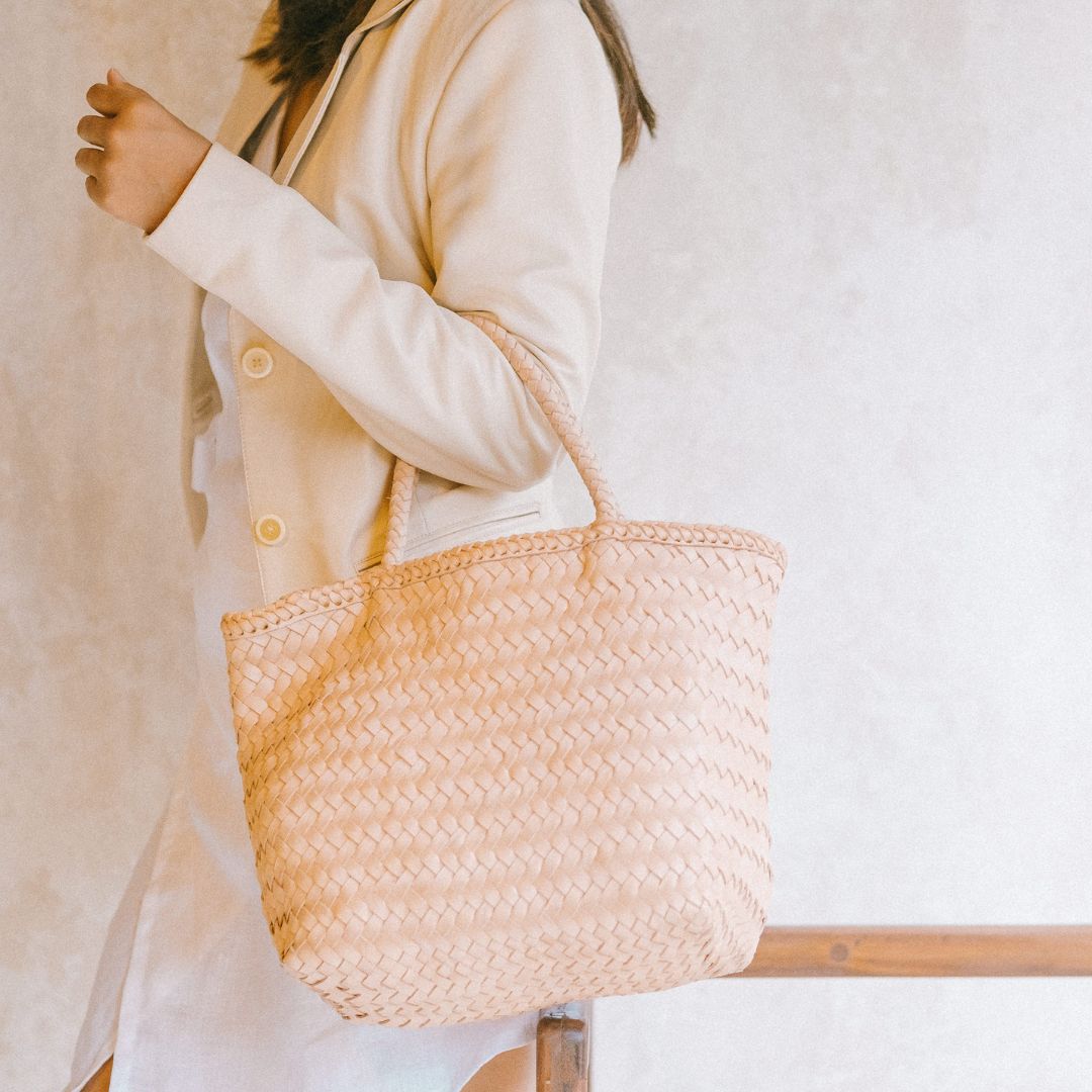 A model is wearing a handbag from vegetable tanned leather in blush color.  