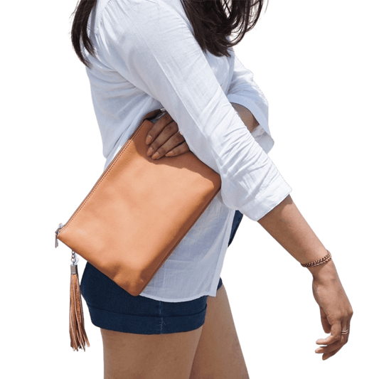 A model hold a 2in1 leather Clutch. It shows the soft texture and the beautiful honey tan color of the goat leather. It is Cloe 2in1 Leather Clutch from Seminyak Leather Bali in Honey Tan color.