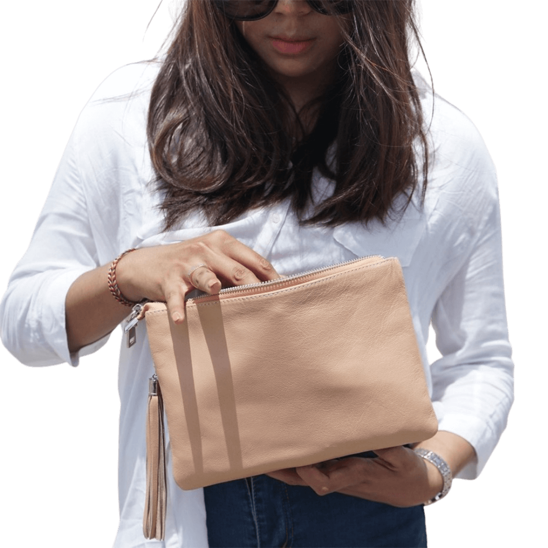 A model shows a 2in1 leather Clutch. It has a zip as a main compartment, and a detachable tassel to make it more stylist. It is Cloe 2in1 Leather Clutch from Seminyak Leather Bali in Nude Pink color.