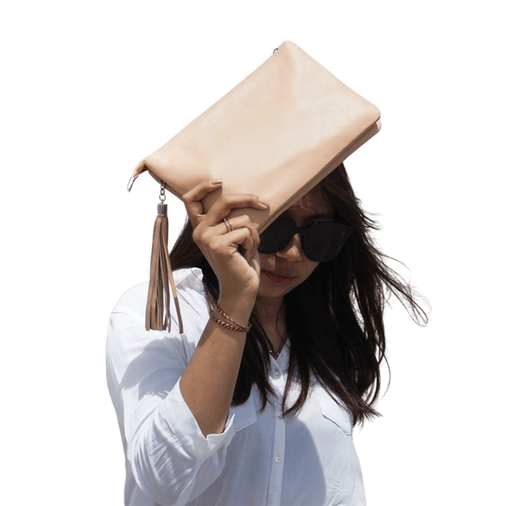 A model cover her face with a 2in1 leather Clutch. It shows the soft texture and beautiful color of the leather. It is Cloe 2in1 Leather Clutch from Seminyak Leather Bali in Nude Pink color.