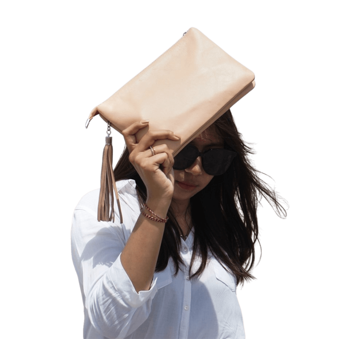A model cover her face with a 2in1 leather Clutch. It shows the soft texture and beautiful color of the leather. It is Cloe 2in1 Leather Clutch from Seminyak Leather Bali in Nude Pink color.