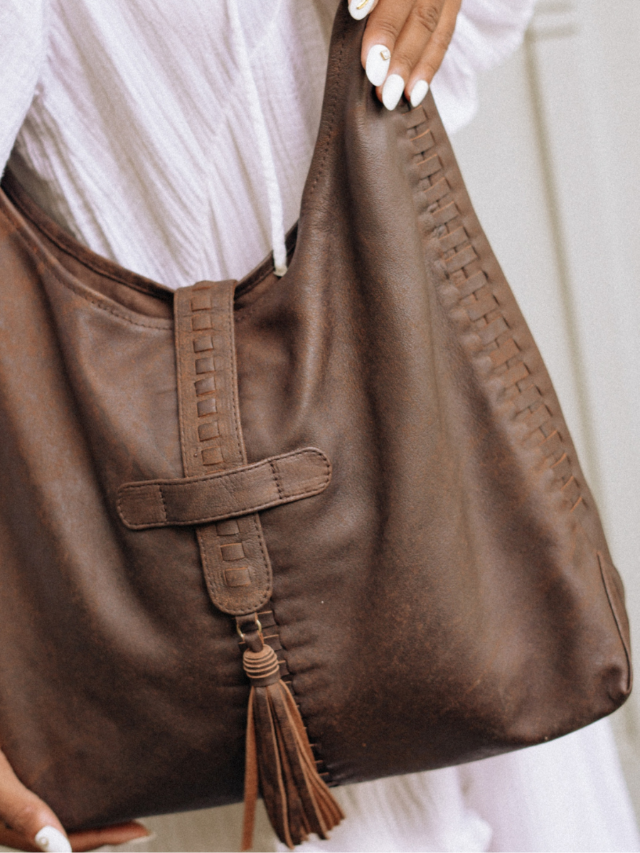 A picture shows the detail of Hella Hobo Bag in Antique Brown. The woven detail and tassel detail fit perfectly with the bag shape. The bag made from sheep leather with 1 main compartment, 1 lining pocket with zip, and 1 phone pocket inside. The bag is quite big, the bag's dimension is 41 x 31 x 10 cm.The bag is from Seminyak Leather Bali