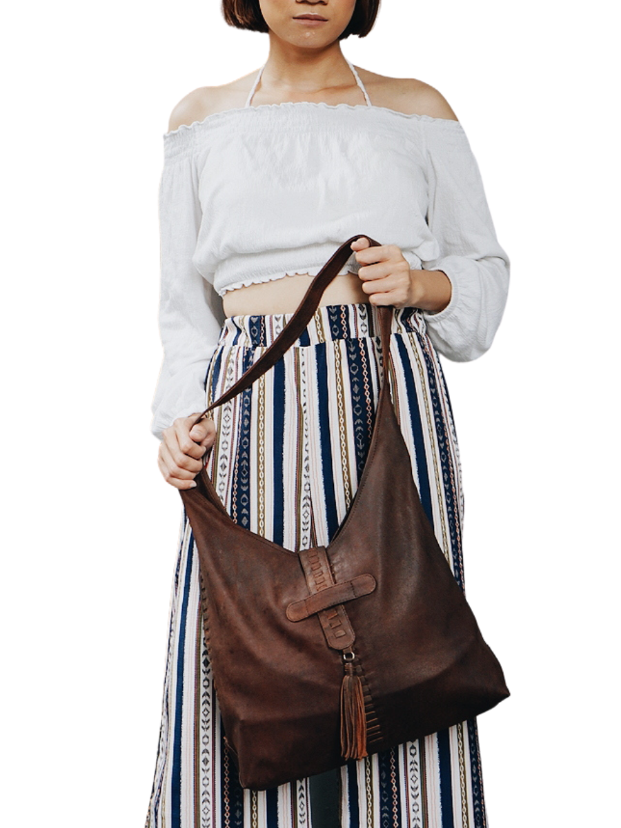 A model with white blouse holding an antique brown bag from Seminyak Leather. The model shows how strong the strap you can put your to go things nicely. It is Ella Hobo Bag. 