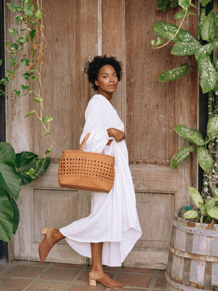 A woman hold tan medium-sized rectangle handbag made of hand-weaved leather with braided handle and chick-eye weave on the body by Seminyak Leather Bali. A blend of modern elegance and artisanal charm, crafted with meticulous attention to detail.