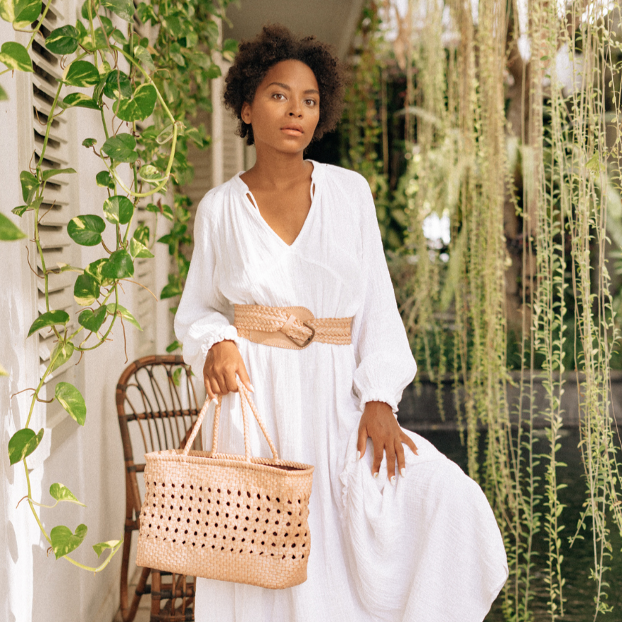 A woman hold blush medium-sized rectangle handbag made of hand-weaved leather with braided handle and chick-eye weave on the body by Seminyak Leather Bali. A blend of modern elegance and artisanal charm, crafted with meticulous attention to detail.