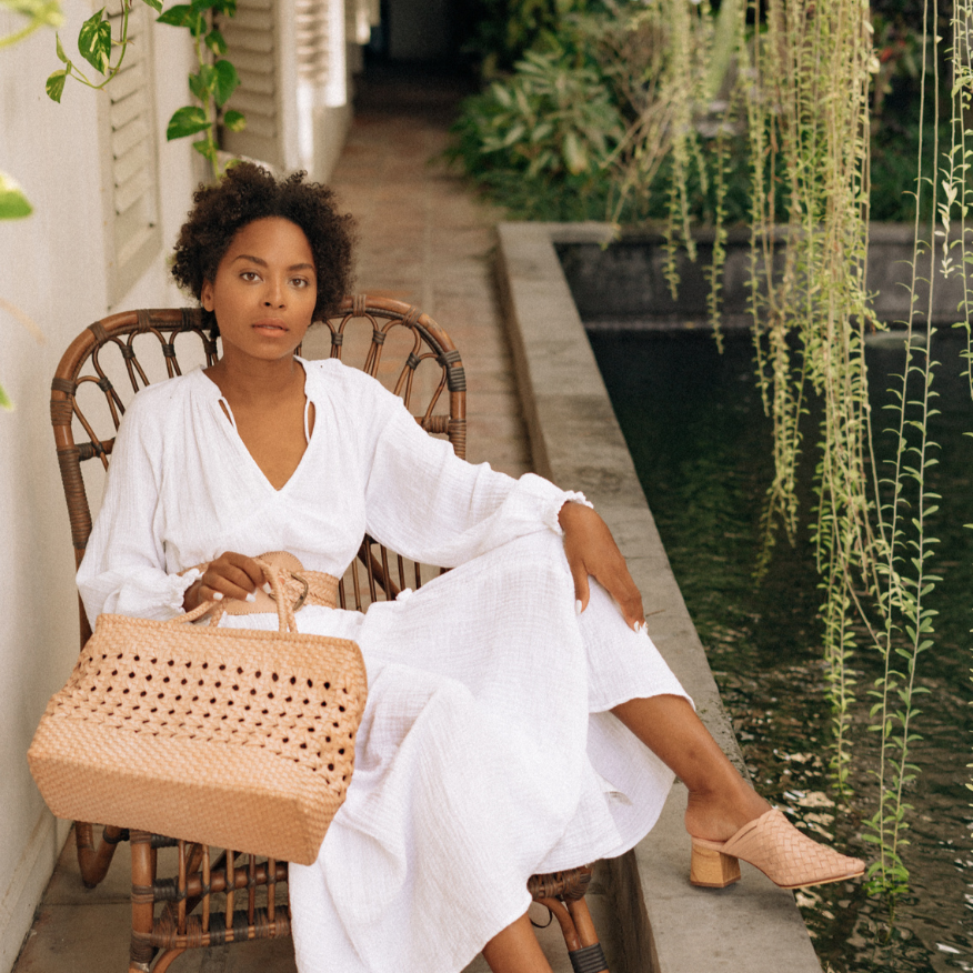 A woman hold blush medium-sized rectangle handbag made of hand-weaved leather with braided handle and chick-eye weave on the body by Seminyak Leather Bali. A blend of modern elegance and artisanal charm, crafted with meticulous attention to detail.