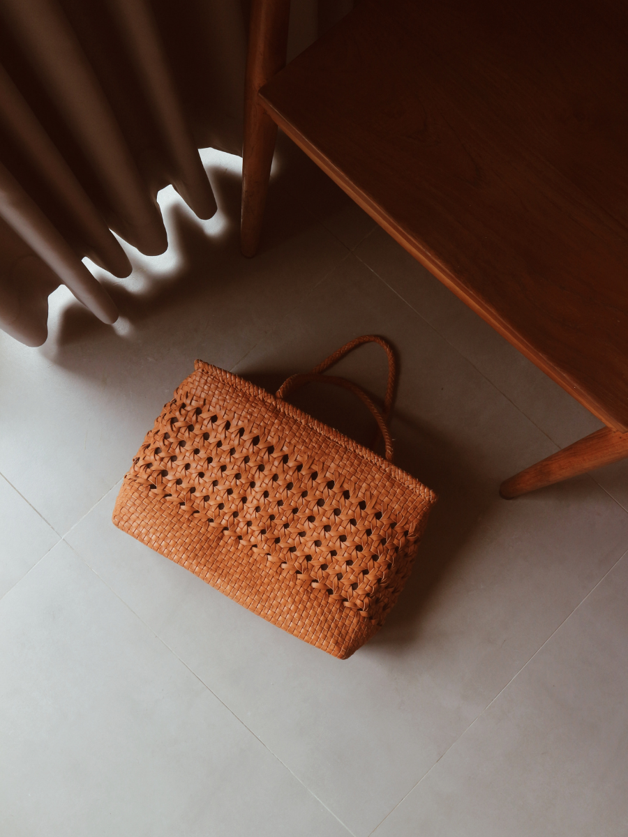 A tan medium-sized rectangle handbag made of hand-weaved leather with braided handle and chick-eye weave on the body by Seminyak Leather Bali. A blend of modern elegance and artisanal charm, crafted with meticulous attention to detail.