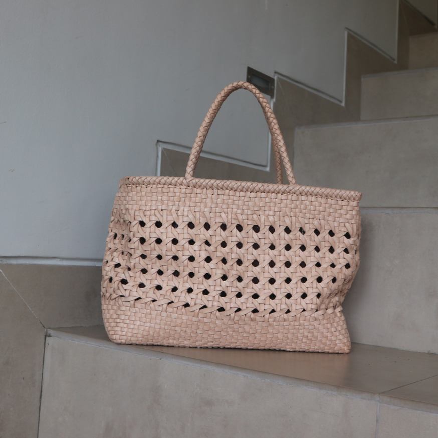 A blush medium-sized rectangle handbag made of hand-weaved leather with braided handle and chick-eye weave on the body by Seminyak Leather Bali. A blend of modern elegance and artisanal charm, crafted with meticulous attention to detail.