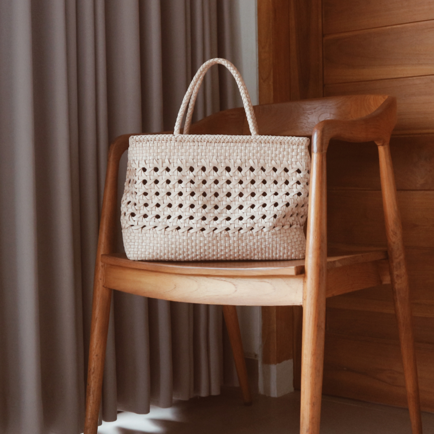 A blush medium-sized rectangle handbag made of hand-weaved leather with braided handle and chick-eye weave on the body by Seminyak Leather Bali. A blend of modern elegance and artisanal charm, crafted with meticulous attention to detail.
