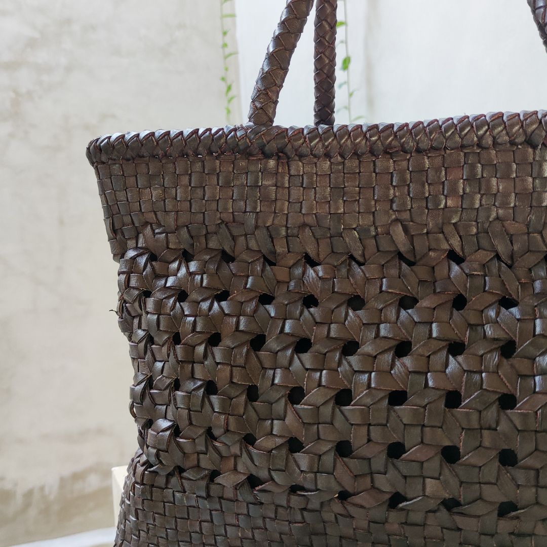 A dark tan medium-sized rectangle handbag made of hand-weaved leather with braided handle and chick-eye weave on the body by Seminyak Leather Bali. A blend of modern elegance and artisanal charm, crafted with meticulous attention to detail.