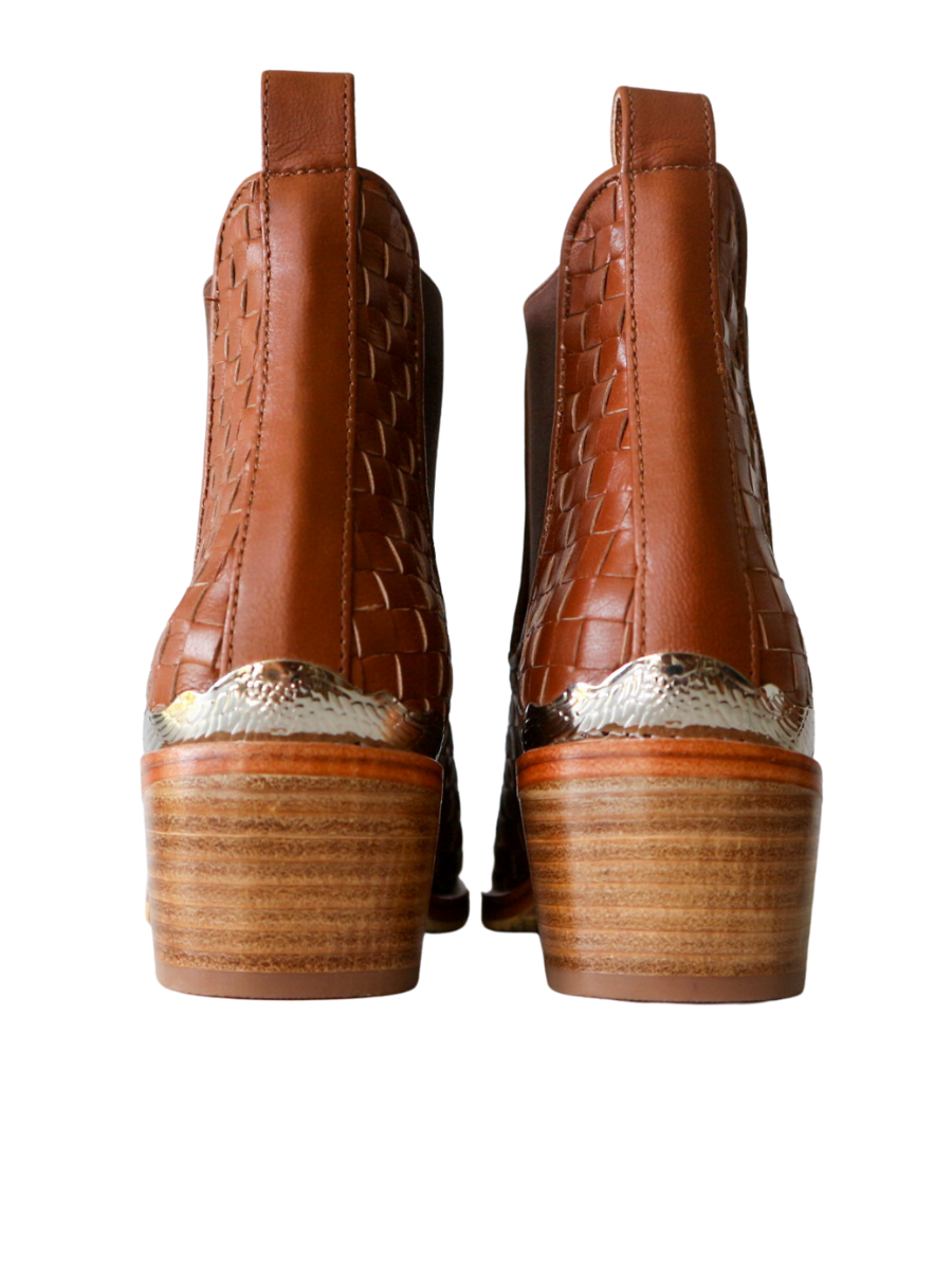 Ankle boots with leather woven detailing in a slim fit cut by Semminyak Leather Bali. Elastic closure with carved metal accents on toe cap and heel. 5 cm wooden heel with a pointy toe design. Stylish and sophisticated footwear with a natural finish, perfect for making a fashion statement.