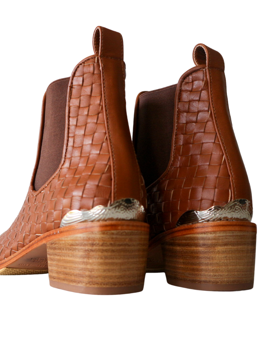 Ankle boots with leather woven detailing in a slim fit cut by Semminyak Leather Bali. Elastic closure with carved metal accents on toe cap and heel. 5 cm wooden heel with a pointy toe design. Stylish and sophisticated footwear with a natural finish, perfect for making a fashion statement.