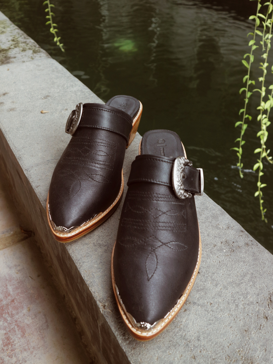 Black pointy toe mules by Seminyak Leather Bali with western-style stitching on vamp and carved metal toe cap. 5 cm wooden Cuban heel in a natural finish. A blend of Western charm and contemporary elegance, all made of leather.